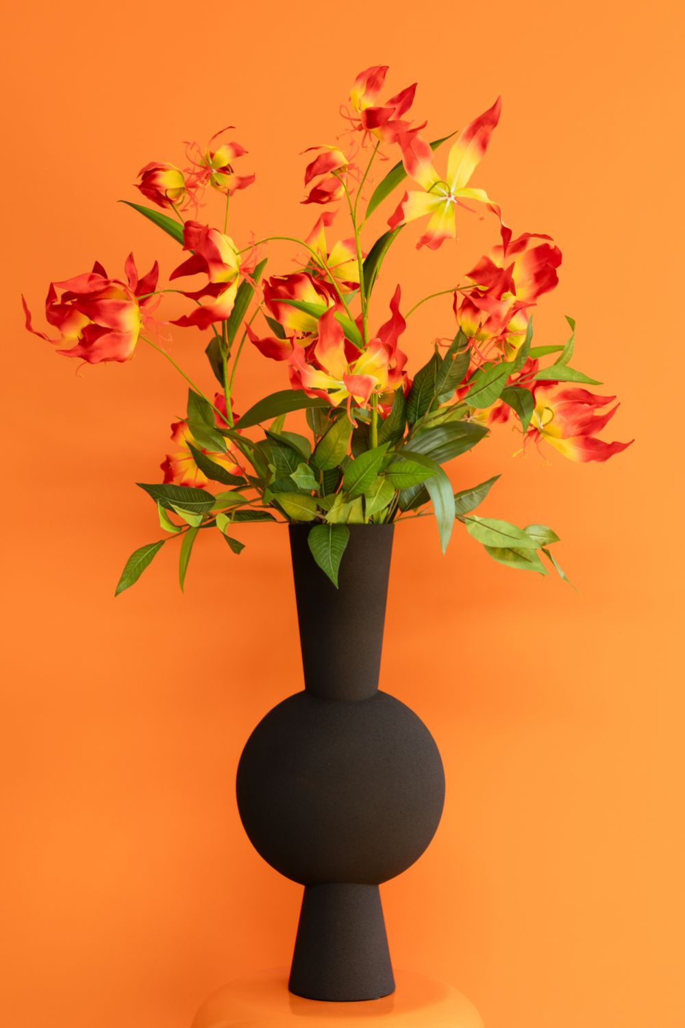 Glorious Gloriosa Kunstboeket met oranje achtergrond